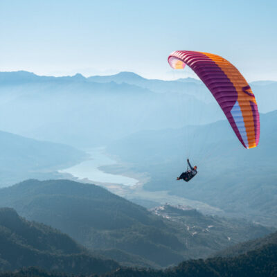 Parapente sur montagnes et vallée fluviale.